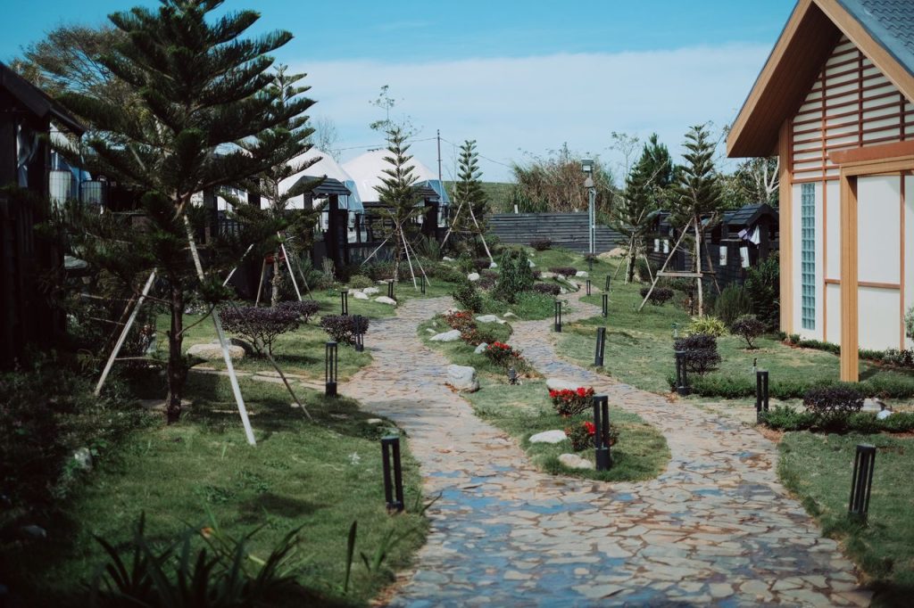 A tranquil Japanese-style garden with stone pathways and a traditional house on a sunny day.