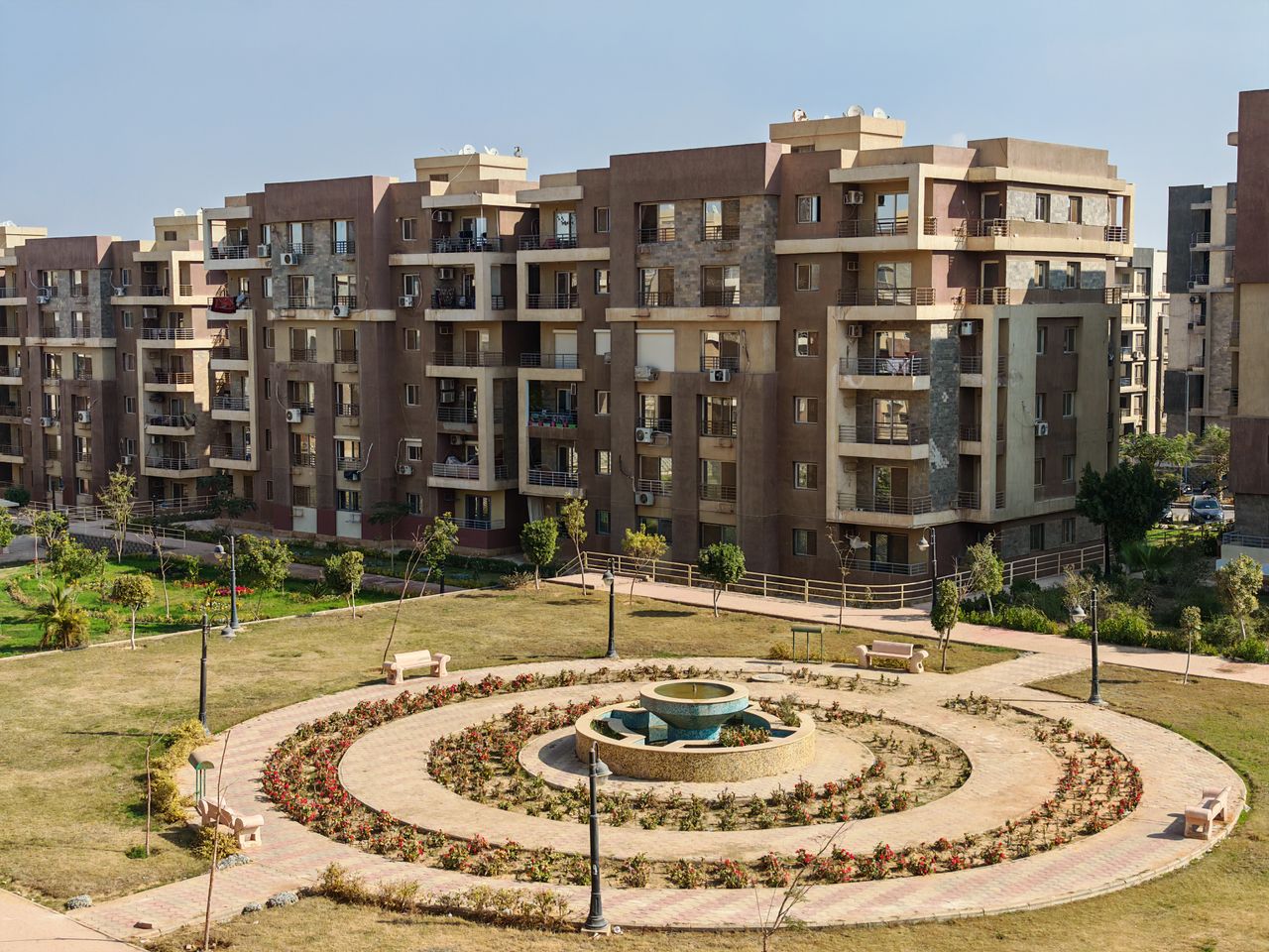 View of a modern apartment complex with a central garden featuring a fountain.